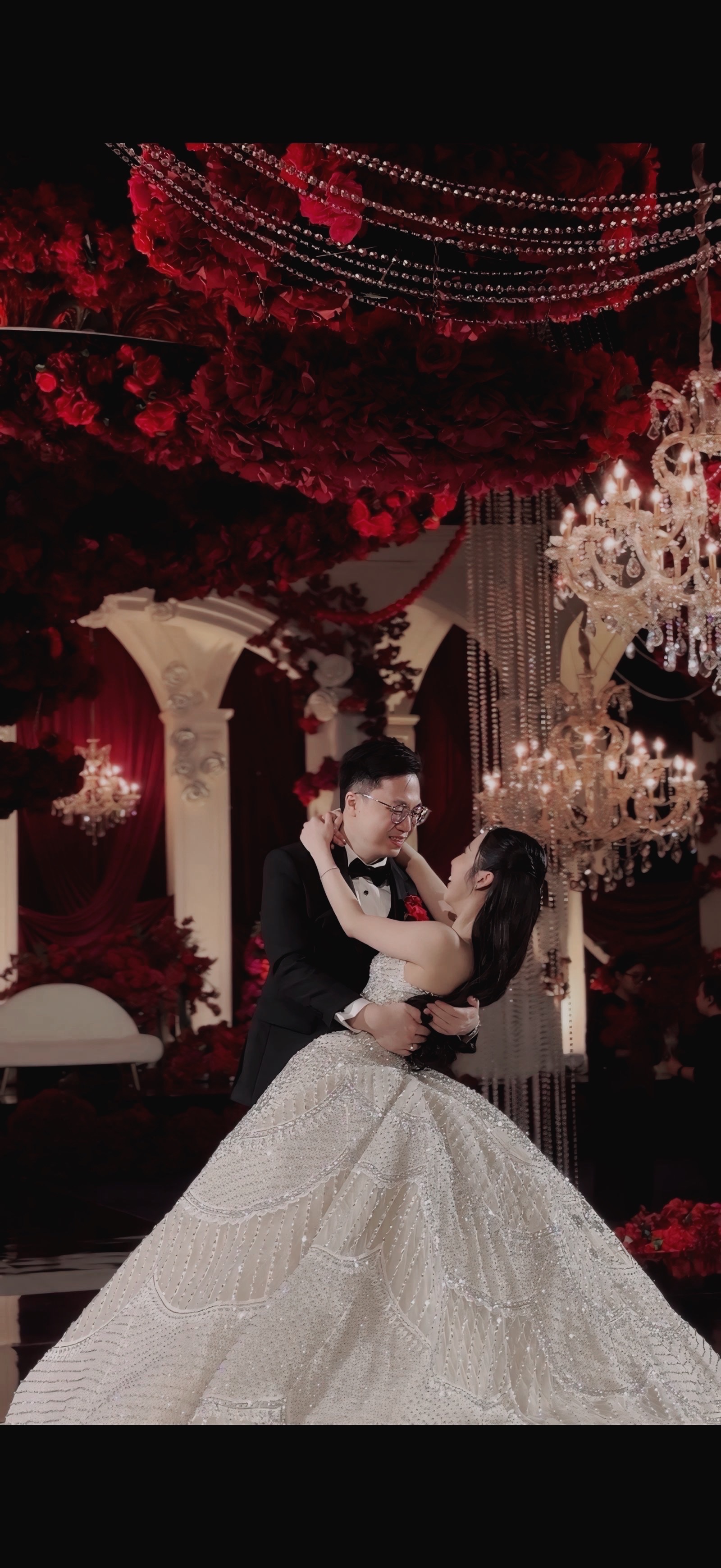 Newlyweds slow dancing among red roses