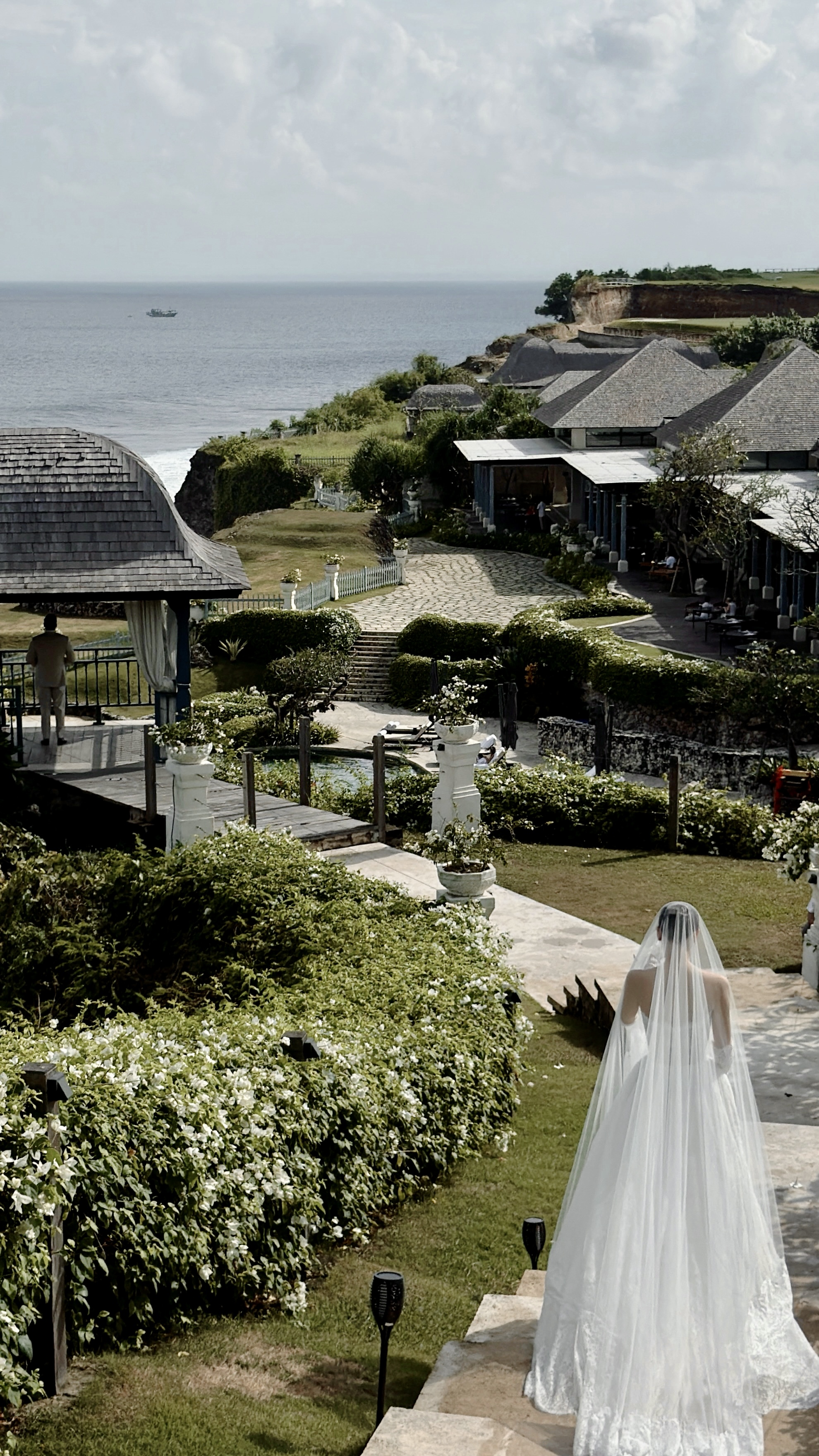 Bride walking toward a cliffside ocean resort